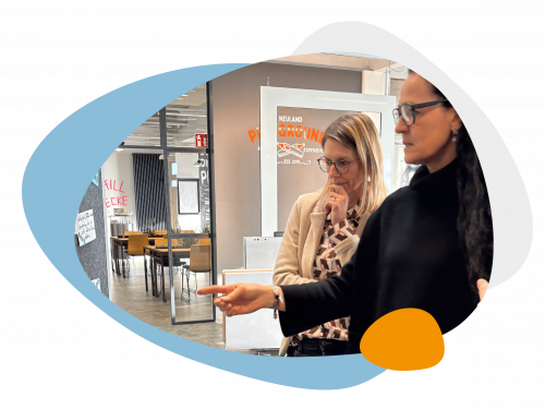 Eine lächelnde Frau unterhält sich mit einer anderen Frau, die einen Block und Stift in Händen hält.